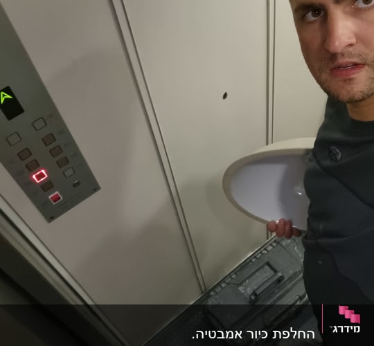 אדם מחזיק כיור קטן במעלית עם ארגז כלים